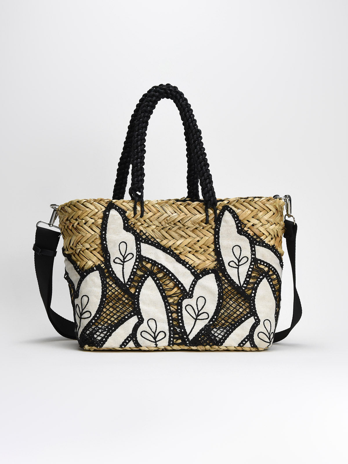 Bolso de rafia con bordado blanco y negro, asas trenzadas y correa ajustable, diseño elegante y práctico.