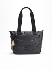 Bolso shopper acolchado negro con asas largas, correa bandolera ajustable y detalle decorativo colgante lateral.