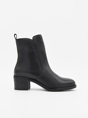 Botín de piel negra con cremallera lateral, tacón medio cuadrado y diseño minimalista elegante.